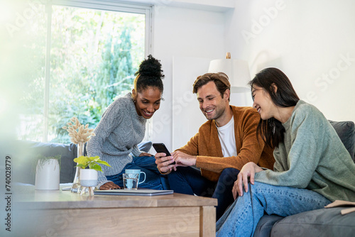Small group of friends gathered in living room while using smart phone