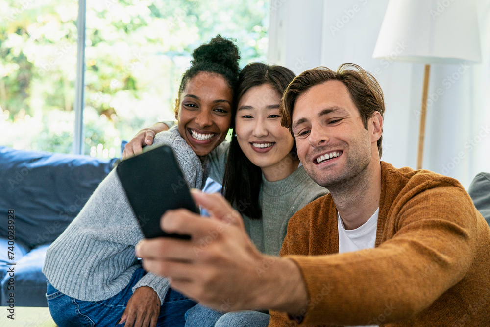 Small group of friends taking a selfie while sitting on sofa Small group of friends taking a selfie while sitting on sofa