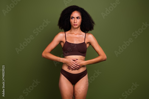 No filter photo of sad upset girl wearing top and panties touching tummy suffering pain disease isolated on khaki color background
