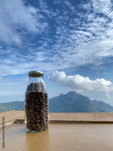A bottle of coffee beans with sky background.