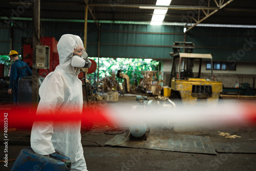 Workers wearing safety suits and gas masks under inspection of chemical tanks in industrial work with hazardous chemicals.