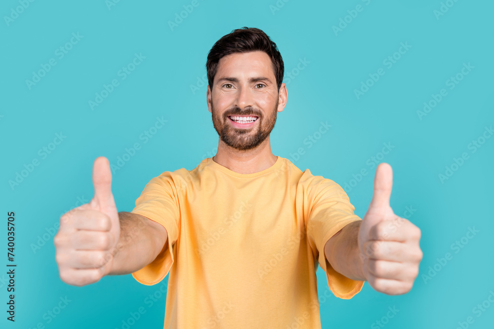 Close up photo of young handsome guy wearing yellow t shirt showing double like symbol golden rate isolated on blue color background Close up photo of young handsome guy wearing yellow t shirt showing double like symbol golden rate isolated on blue color background