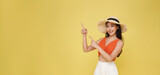 Young elegant beautiful Asian woman dressed in summer clothes smiling and pointing to empty copy space isolated on yellow background.