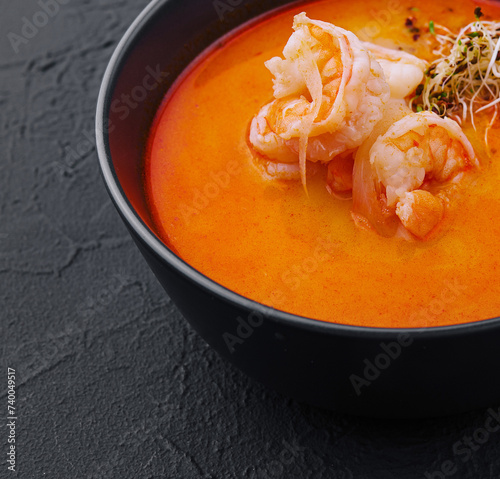 Traditional Thai soup Tom Yam in black bowl photo