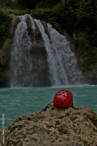 Photos Helmet perched on top of a rock with a waterfall and a lake in the background