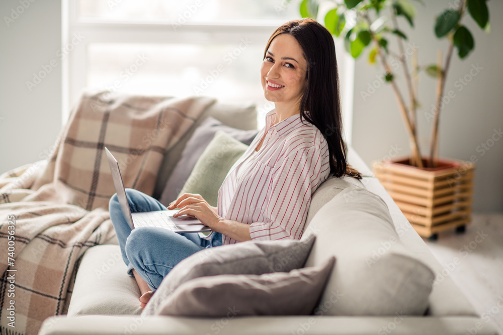 Full body profile photo of cheerful nice lady sit comfy couch use wireless laptop eshopping free time house inside Full body profile photo of cheerful nice lady sit comfy couch use wireless laptop eshopping free time house inside
