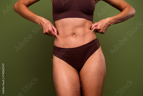 Cropped no retouch photo of female flawless body waist touch fat cells cellulite isolated on khaki color background © deagreez