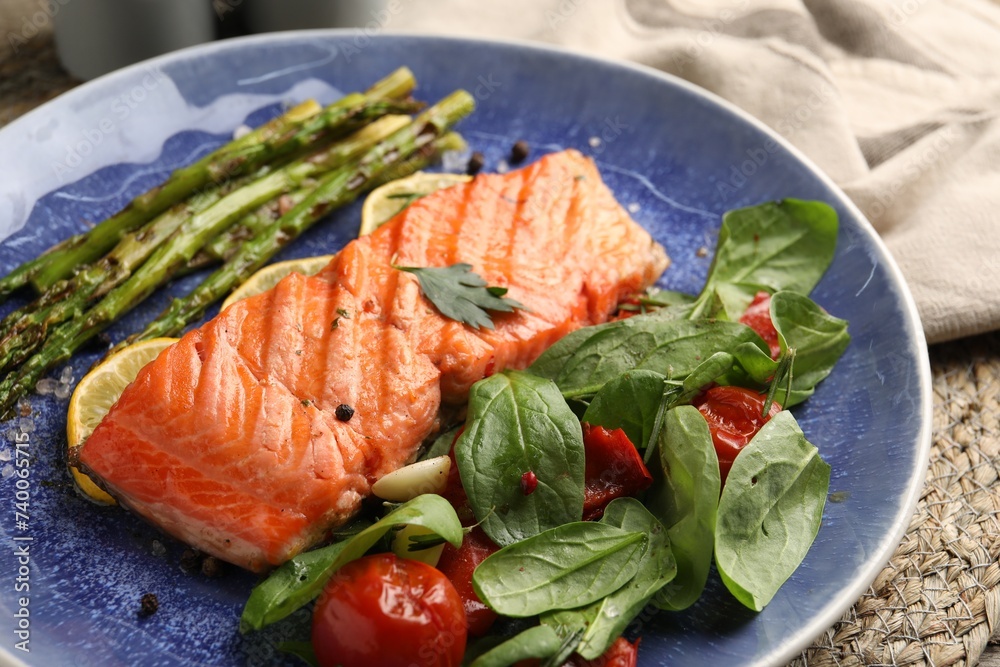 Tasty grilled salmon with tomatoes, asparagus, spinach and spices on table, closeup Tasty grilled salmon with tomatoes, asparagus, spinach and spices on table, closeup