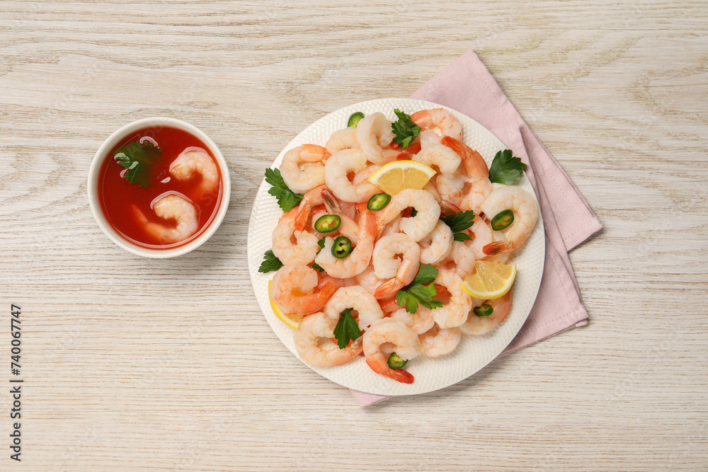 Tasty boiled shrimps with cocktail sauce, chili, parsley and lemon on light wooden table, flat lay Tasty boiled shrimps with cocktail sauce, chili, parsley and lemon on light wooden table, flat lay