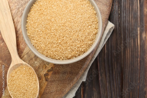 Brown sugar in bowl and spoon on wooden table, flat lay