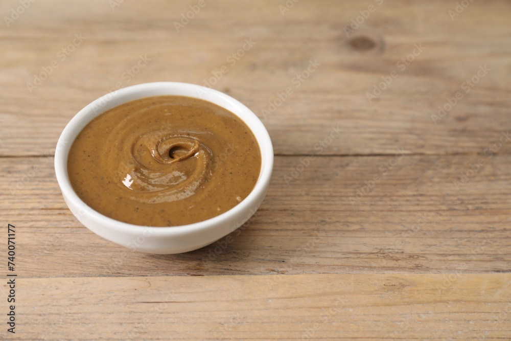 Obraz premium Delicious nut butter in bowl on wooden table, closeup. Space for text