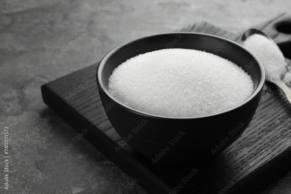 Granulated sugar in bowl on grey textured table, closeup. Space for text Granulated sugar in bowl on grey textured table, closeup. Space for text