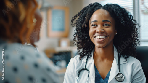 Smiling African american female doctor discussing treatment with patient in medical office. Therapist, general practitioner with stethoscope consulting patient during medical checkup visit photo