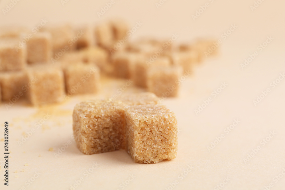 Brown sugar cubes on beige background, closeup. Space for text Brown sugar cubes on beige background, closeup. Space for text