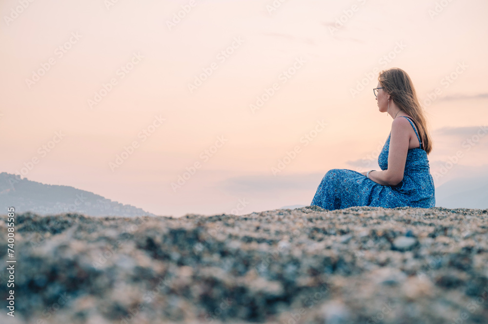 Woman sits on the beach and looks at the sea in Alanya city