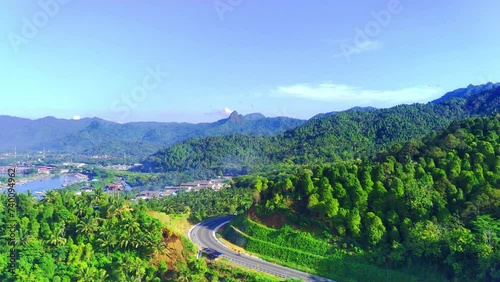 A scenic aerial view of a highway surrounded by trees and mountains in JLS Trenggalek. Drone footage photo