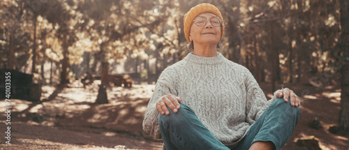 Head shot portrait close up of one middle age old woman resting and relaxing doing yoga in the forest of mountain in the nature. One mature female person enjoying having fun lifestyle.. photo
