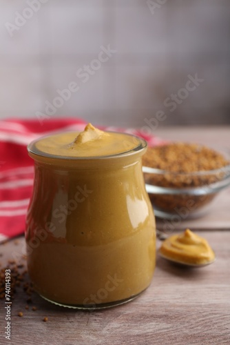 Tasty mustard sauce in jar on wooden table, closeup