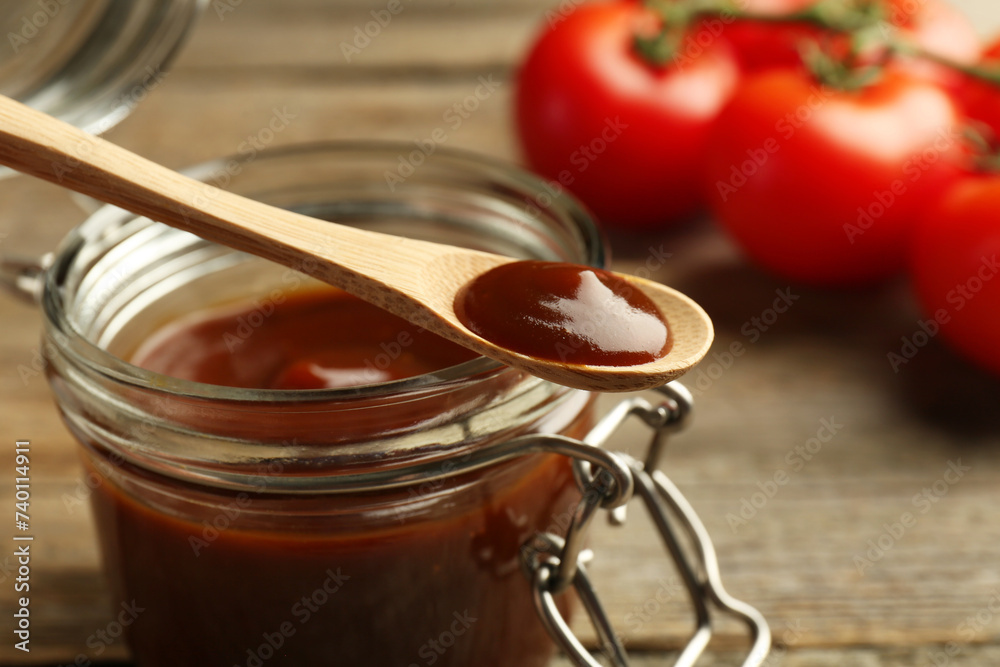 Tasty barbeque sauce in jar and spoon on table, closeup Tasty barbeque sauce in jar and spoon on table, closeup