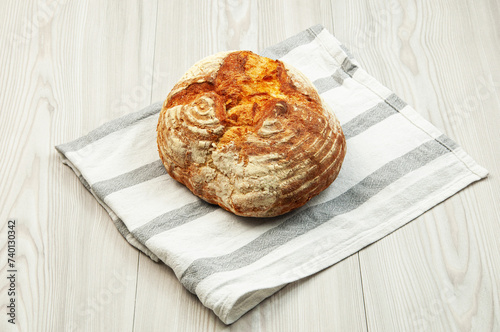 baked Italian bread on a light wooden table. ciabatta on a white towel on a wooden background	