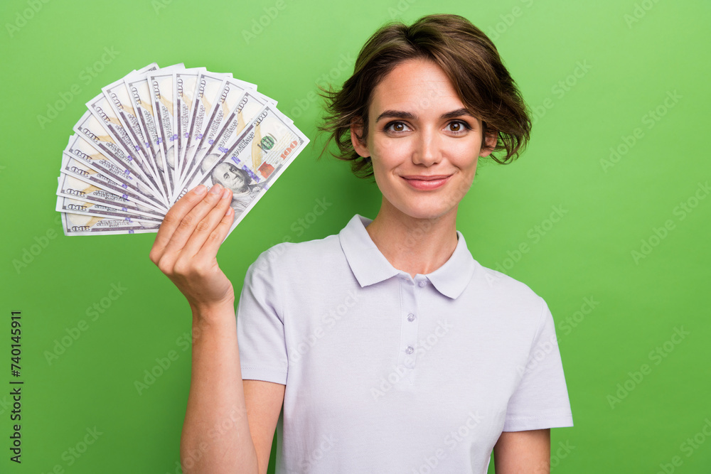 Photo of sweet cheerful lady wear grey t-shirt rising cash fan smiling isolated green color background Photo of sweet cheerful lady wear grey t-shirt rising cash fan smiling isolated green color background