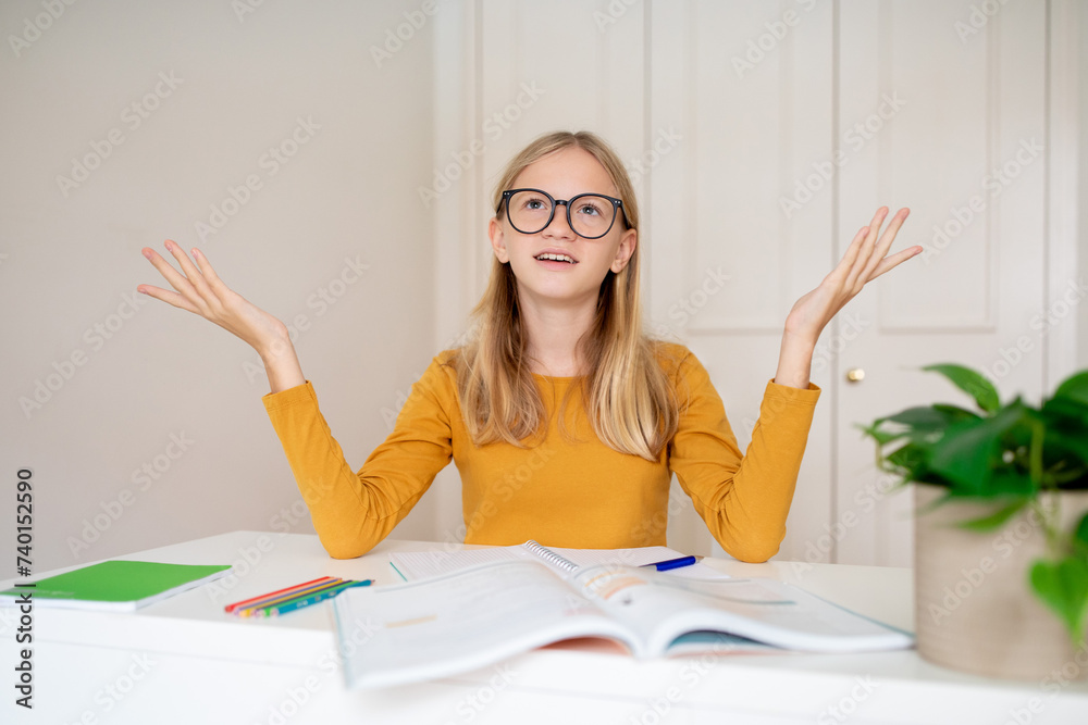 Confused teen girl studying with books at home and raising her hands Confused teen girl studying with books at home and raising her hands