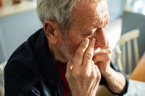 Senior man contemplating with hand on face at home photo