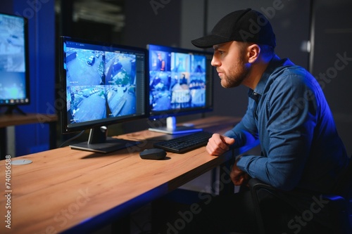 Male security guard monitoring modern CCTV cameras indoors photo