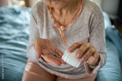 Close up of a senior woman taking pill in bed at home photo