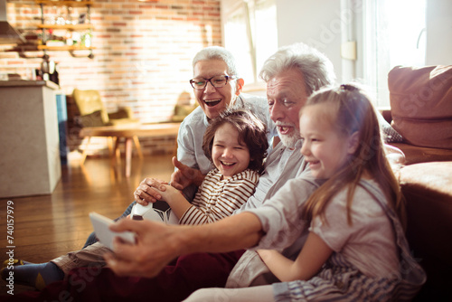 Happy grandparents taking a selfie with grandchildren on the couch at home photo
