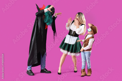 Father in vampire costume scaring his family in carnival masks on purple background