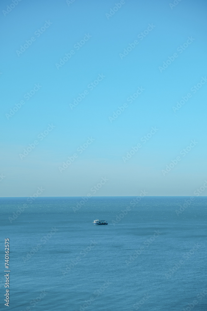 ship goes into the horizon of the blue sea, leaving a trail on the surface of the water landscape. Aerial view, concept of sea travel, cruises