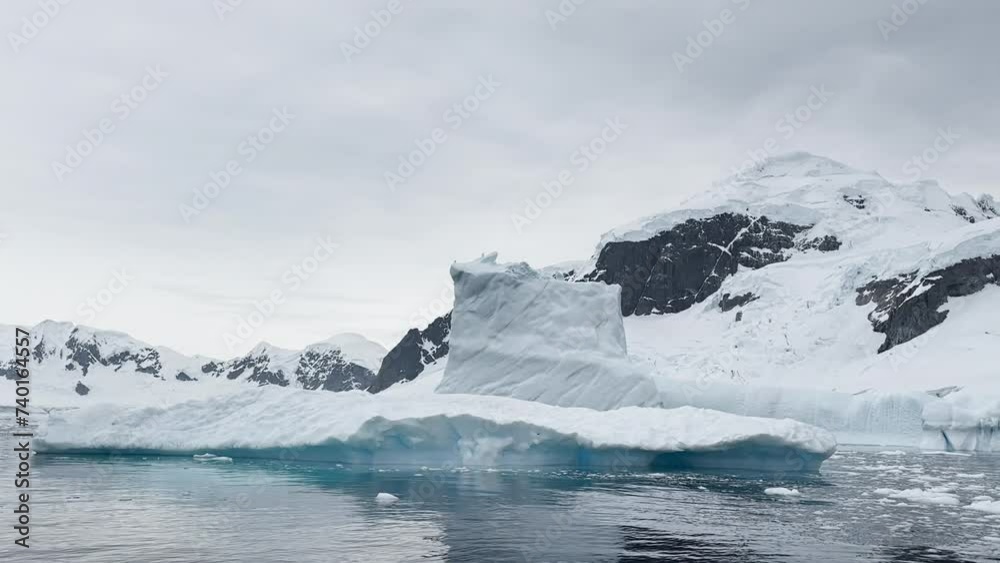 A huge high breakaway glacier is passing by in the southern ocean off the coast of Antarctica, the Antarctic Peninsula, the Southern Circle, azure water, cloudy weather A huge high breakaway glacier is passing by in the southern ocean off the coast of Antarctica, the Antarctic Peninsula, the Southern Circle, azure water, cloudy weather