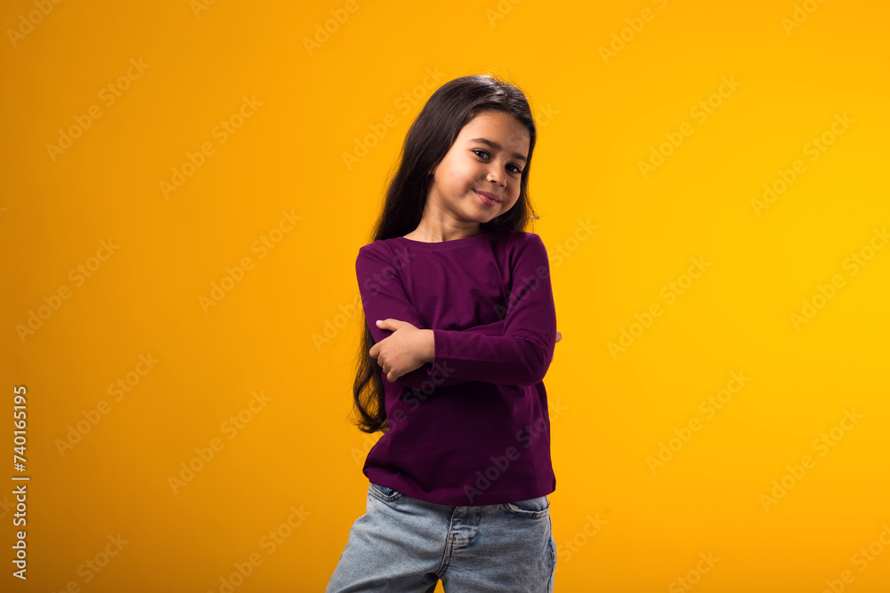Smiling kid girl looking at camera over yellow background. Childhood and positive emotions concept Smiling kid girl looking at camera over yellow background. Childhood and positive emotions concept