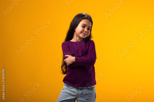 Smiling kid girl looking at camera over yellow background. Childhood and  positive emotions concept © Aleksej