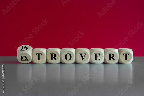 Introvert or extrovert symbol. Turned a cube and changed the word introvert to extrovert. Beautiful gray table, red background, copy space. Psychological and Introvert or extrovert concept.