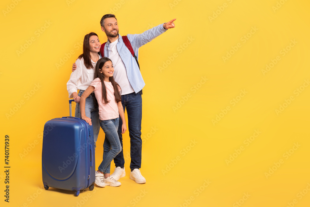 Family ready for vacation pointing to travel offer, yellow background Family ready for vacation pointing to travel offer, yellow background