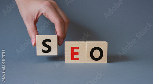 SEO - Search Engine Optimization symbol. Wooden blocks with words SEO. Businessman hand. Beautiful grey background. Business and SEO concept. Copy space.