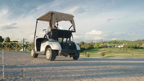 Woman riding luxury golf cart to arrive on place for playing sport game, golf cart for two people in motion against amazing golf course and countryside background