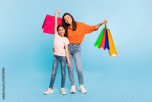 Happy young mother and daughter posing with shopping bags, studio