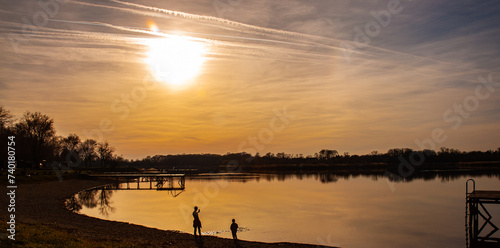 Children silhouette on the beach next to water in sunset. The lake Zobnatica is located near Backa Topola.