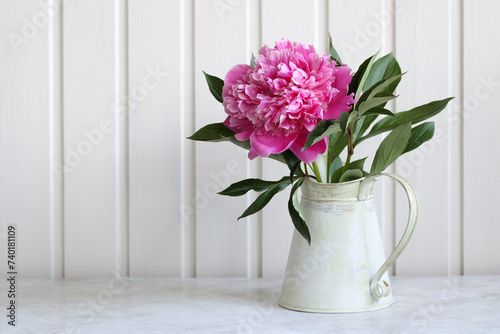 A peony in full bloom in a jug on the table in the cottage. a garden flower. cottage core.