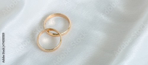 wedding background. gold wedding rings on white satin fabric. marriage is a concept. copy space.