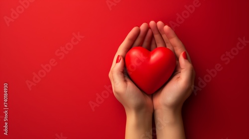 hands holding a simple red heart over a red background