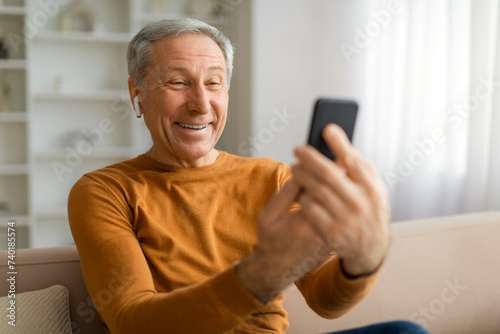 Happy elderly man have video chat with family, using phone