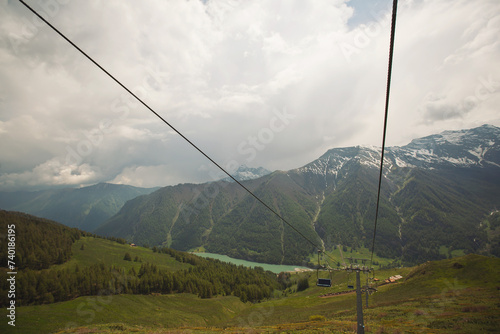 two rows of cable cars one going uphill while one going downhill. Cable Cars On An Alpine Mountainside. Cable car trip to viewpoints in the mountains. Tourists enjoy beautiful views.