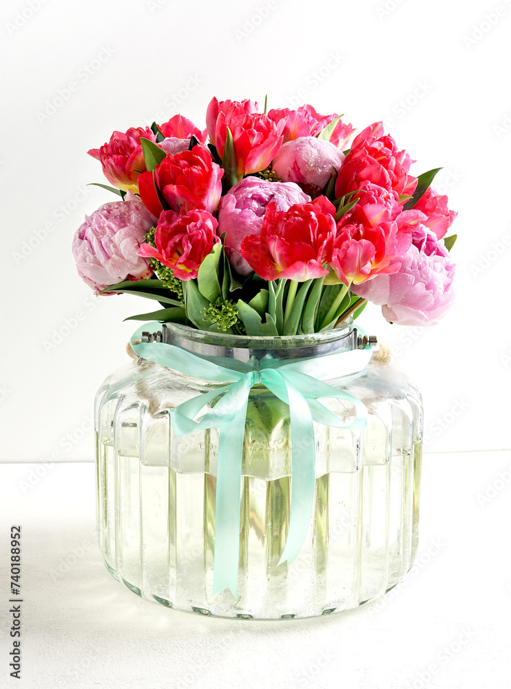 Beautiful pink peony flowers bouquet in glass vase on white background