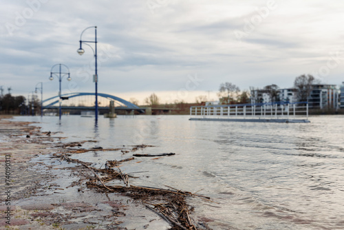 Flooded riverside Magdeburg embankment promenade Submerged street lamp posts Bridge Background. Cobblestone pavement road walkway close drive prohibited due weather seasonal disaster. Climate change photo