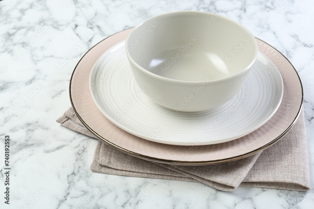 Clean plates, bowl and napkin on white marble table, closeup. Space for text Clean plates, bowl and napkin on white marble table, closeup. Space for text