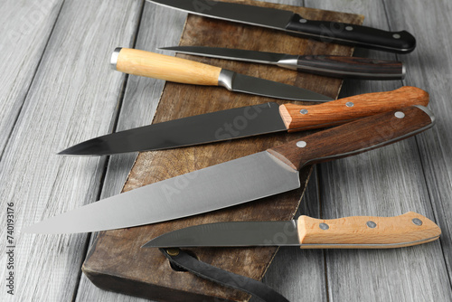 Many different knives and board on light wooden table